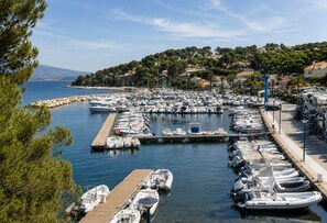 A marina with numerous boats docked, a wooden pier, and a backdrop of a hilly landscape with buildings. - Family Villa with Ocean View (Saint-Cyr-sur-Mer)