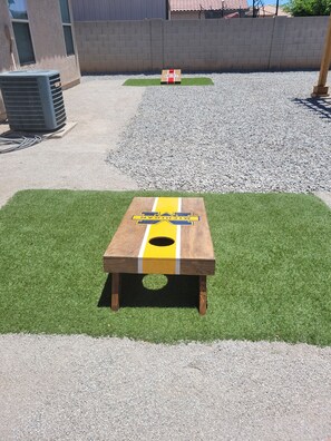 A wooden table with a yellow and blue design, placed on a patch of artificial grass. - 3 bedroom Oasis, Steps from Glendale Stadium (Phoenix)