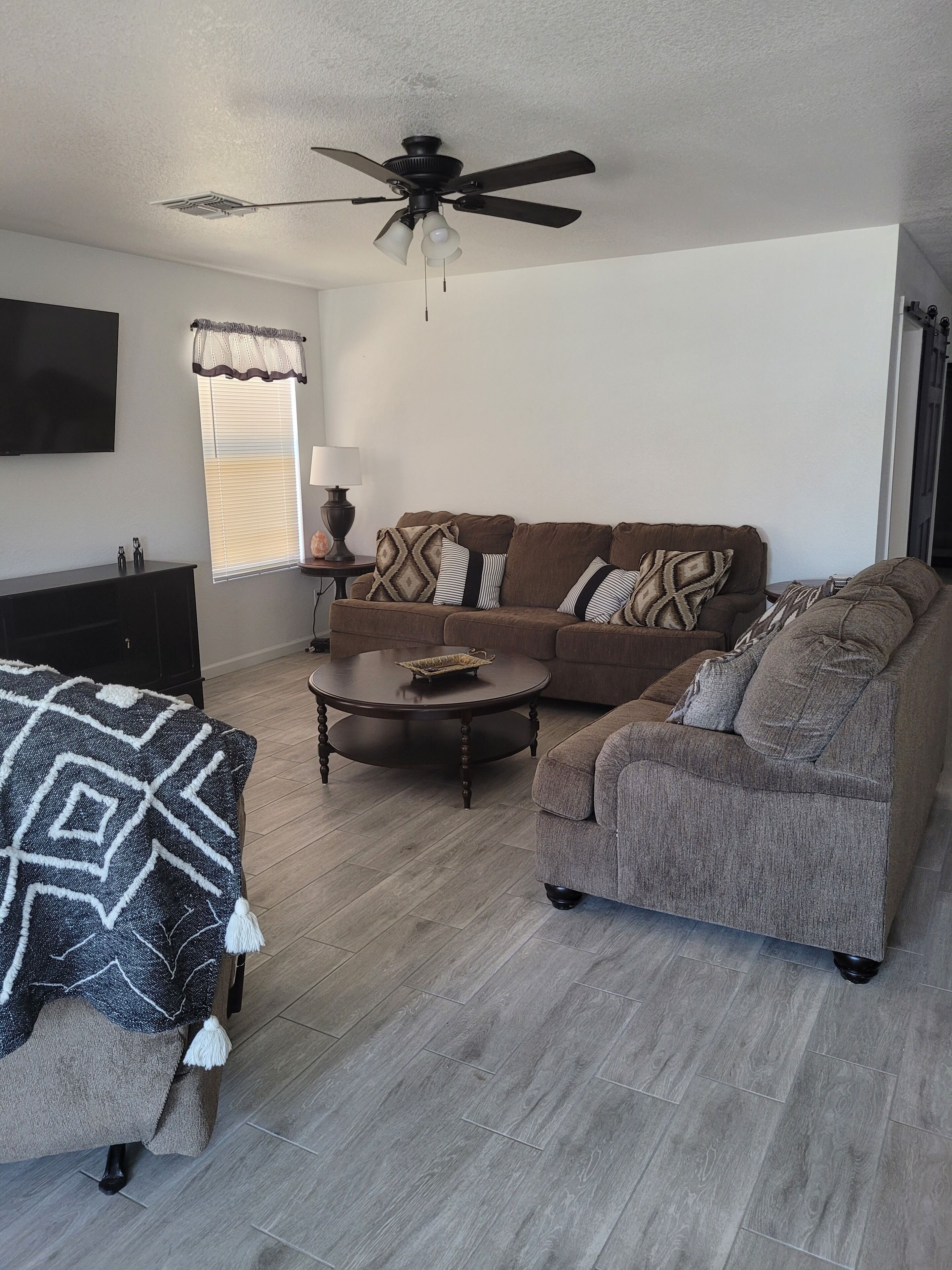 A living room with a sofa, coffee table, and a ceiling fan.