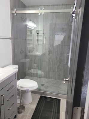 A bathroom with a glass-enclosed shower, a toilet, and a vanity with drawers. - 3 bedroom Oasis, Steps from Glendale Stadium (Phoenix)