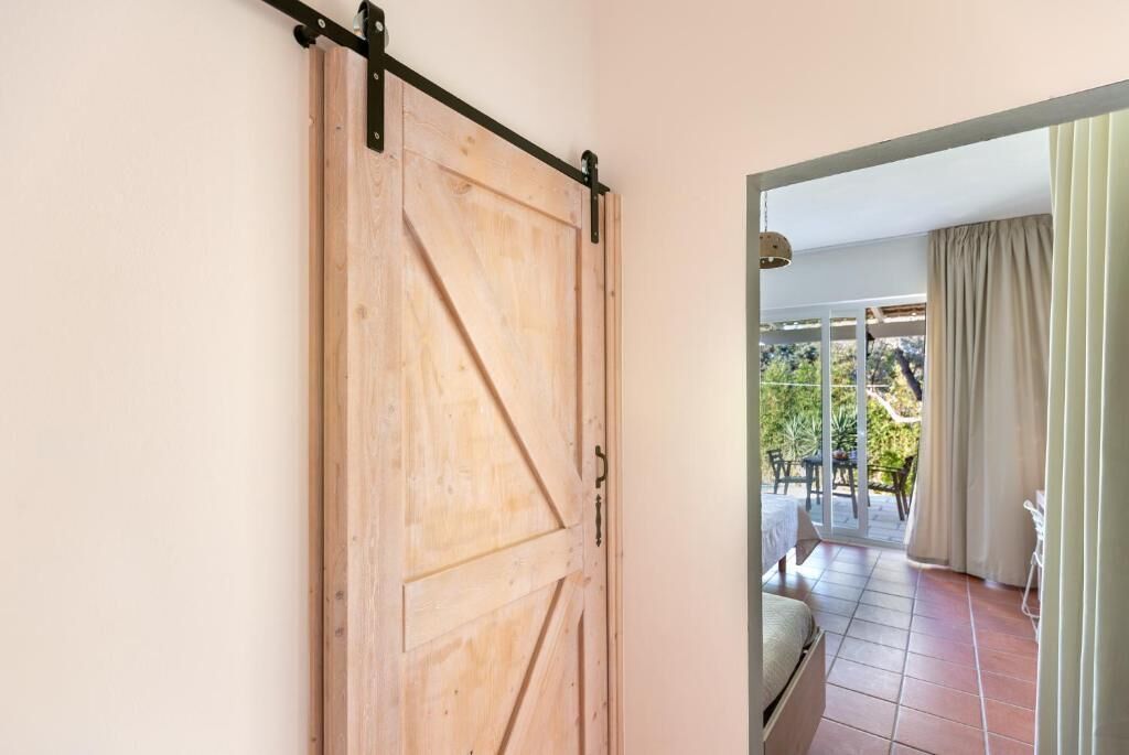Puerta corredera de madera que da a un patio al aire libre con una cama y una mesa.