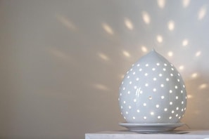 A white spherical object with holes, casting light patterns on a wall.