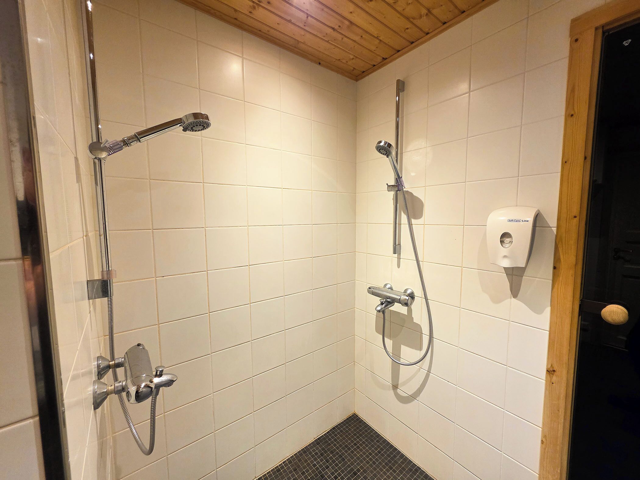 Un espace douche avec des murs carrelés et un plafond en bois.