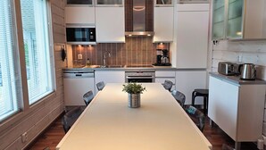 A modern kitchen with a central island, built-in appliances, and a view to the left. - Villa Chalet, Himos Länsihuippu (Jämsä)