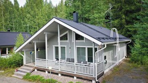 A two-story cabin with a balcony, large windows, and a chimney.