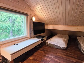 A compact room with a bed, a desk with a computer, and a TV. - Villa Chalet, Himos Länsihuippu (Jämsä)