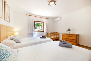 A hotel room with two beds, a wooden dresser, a crib, and a window with curtains. - Mallorcan Villa with Pool in S'Amarador (Santanyí)