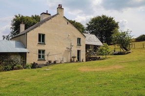 A two-story house with a sloped roof, a chimney, and a small front porch with outdoor furniture.