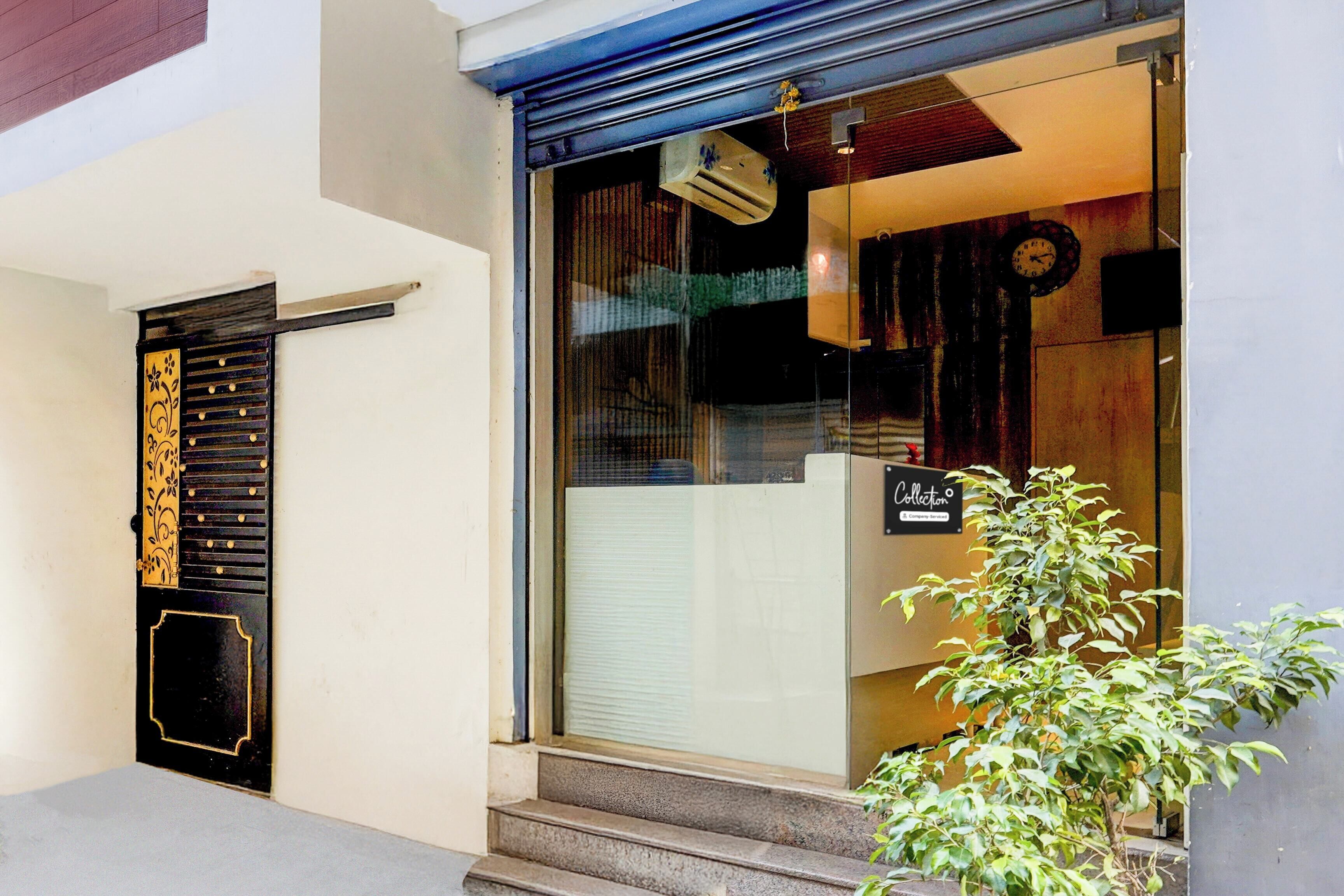 Una entrada de edificio con una puerta negra, un ventanal y un letrero que dice 'Collection'.
