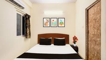 Habitación de hotel con cama, mesita de noche, planta en maceta y tres cuadros en la pared.