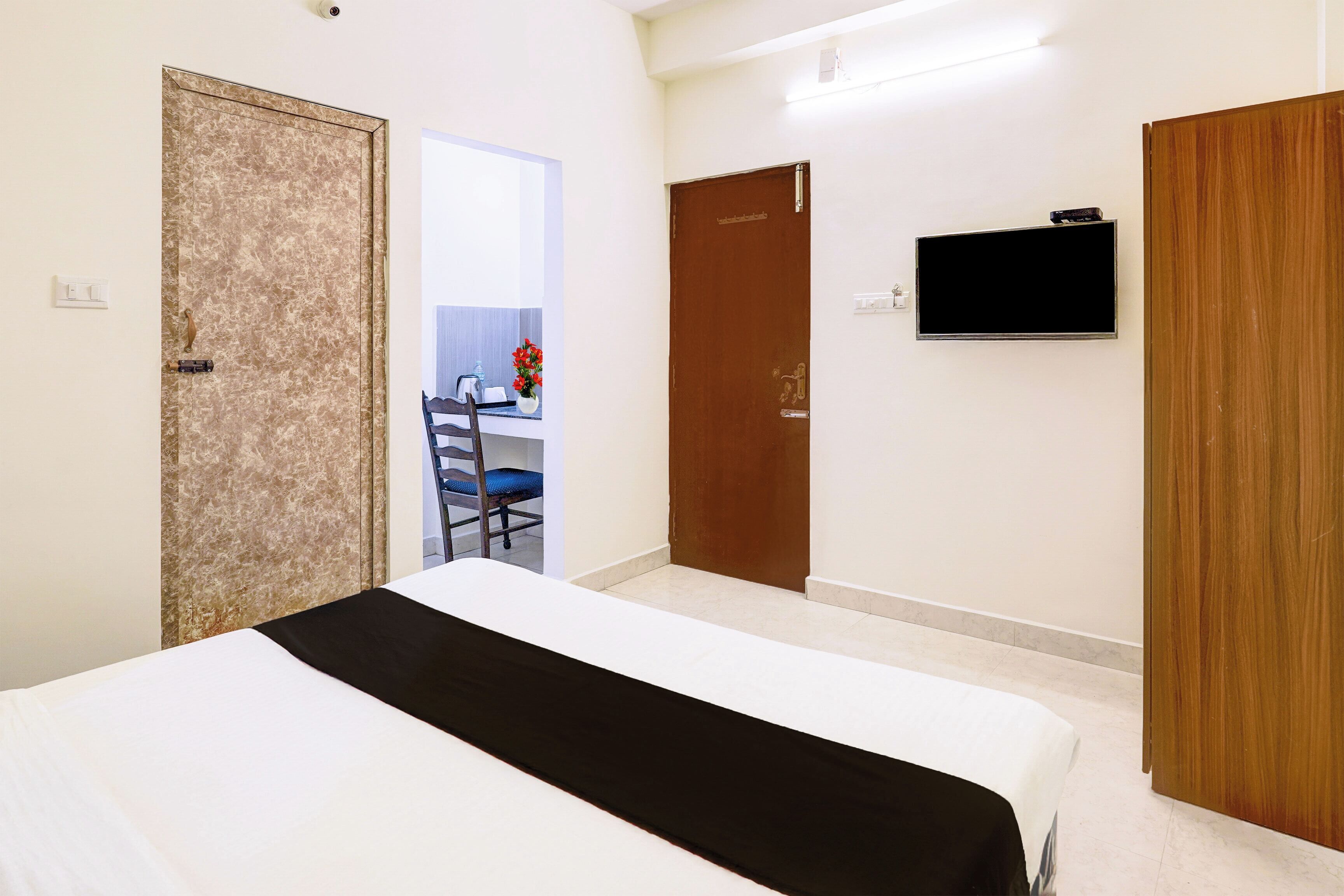 Ein Hotelzimmer mit einem Bett, einem Schreibtisch mit Stuhl, einem Fernseher und einer Tür.