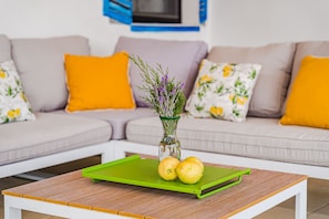 Un salon avec une table basse en bois, un vase rempli de fleurs et des citrons disposés sur un plateau vert.