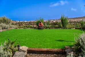 A well-maintained lawn with a statue in the center, surrounded by various shrubs and plants. - Vacation studio for 3 people in La Laguna (La Vega)