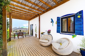 A covered outdoor seating area with wooden flooring, wicker chairs, and a view of the cityscape. - Vacation studio for 3 people in La Laguna (La Vega)