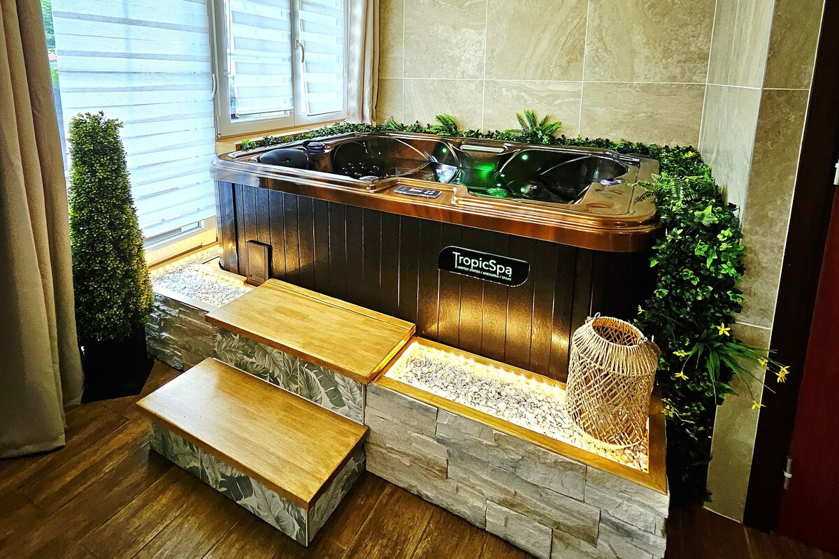 A spa area with a hot tub, stone walls, and a window with blinds.