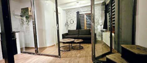 A modern living room with a sofa, a coffee table, and a glass door leading to another room.