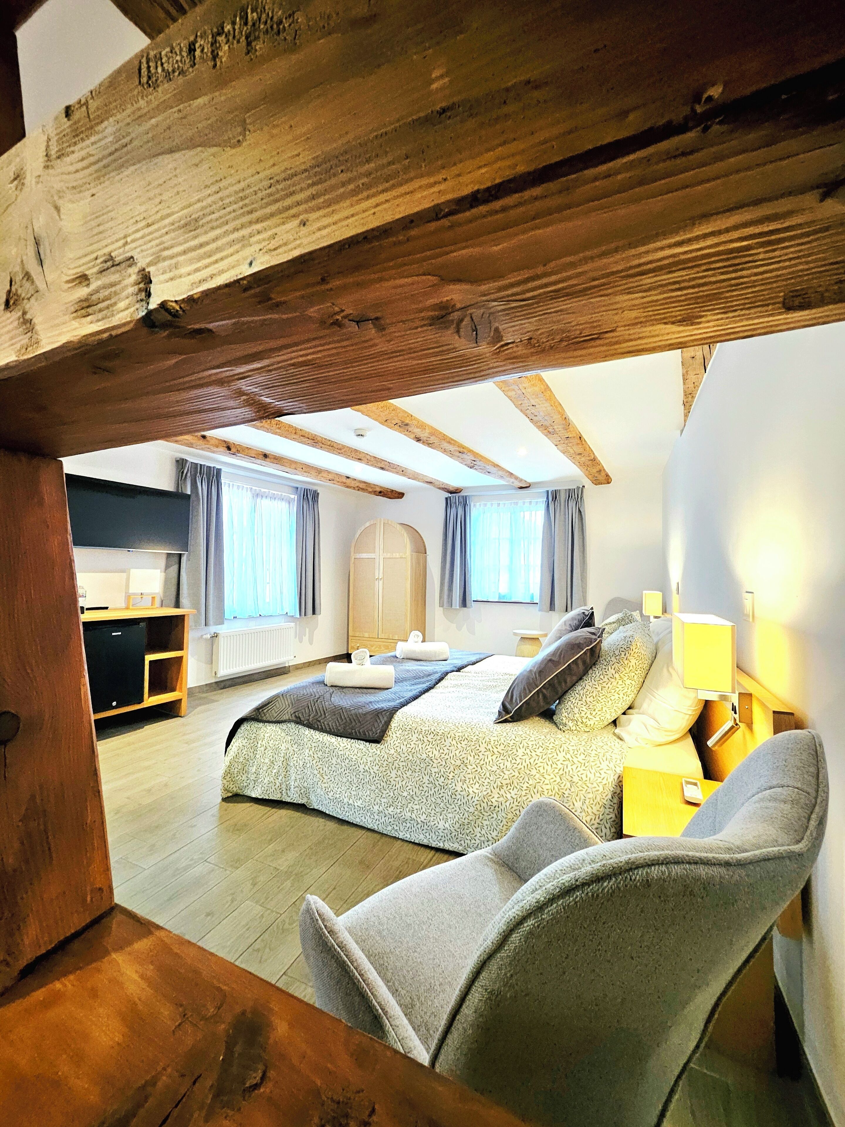 A bedroom with a large bed, a desk, and a wardrobe.