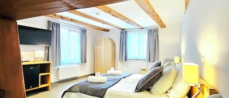 A bedroom with a large bed, a desk, and a wardrobe.