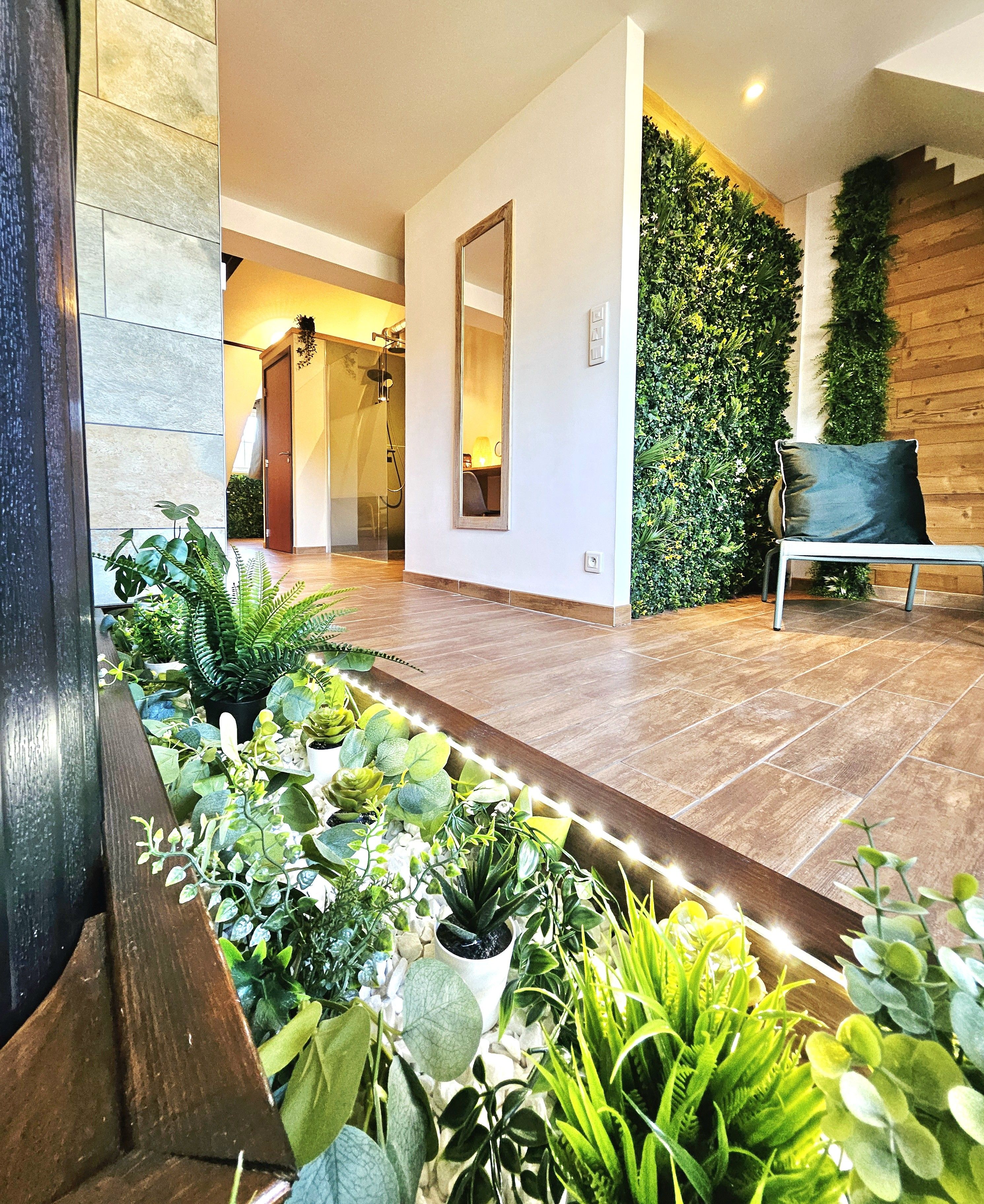 A modern interior with a living area, a wooden bench, and a variety of potted plants.