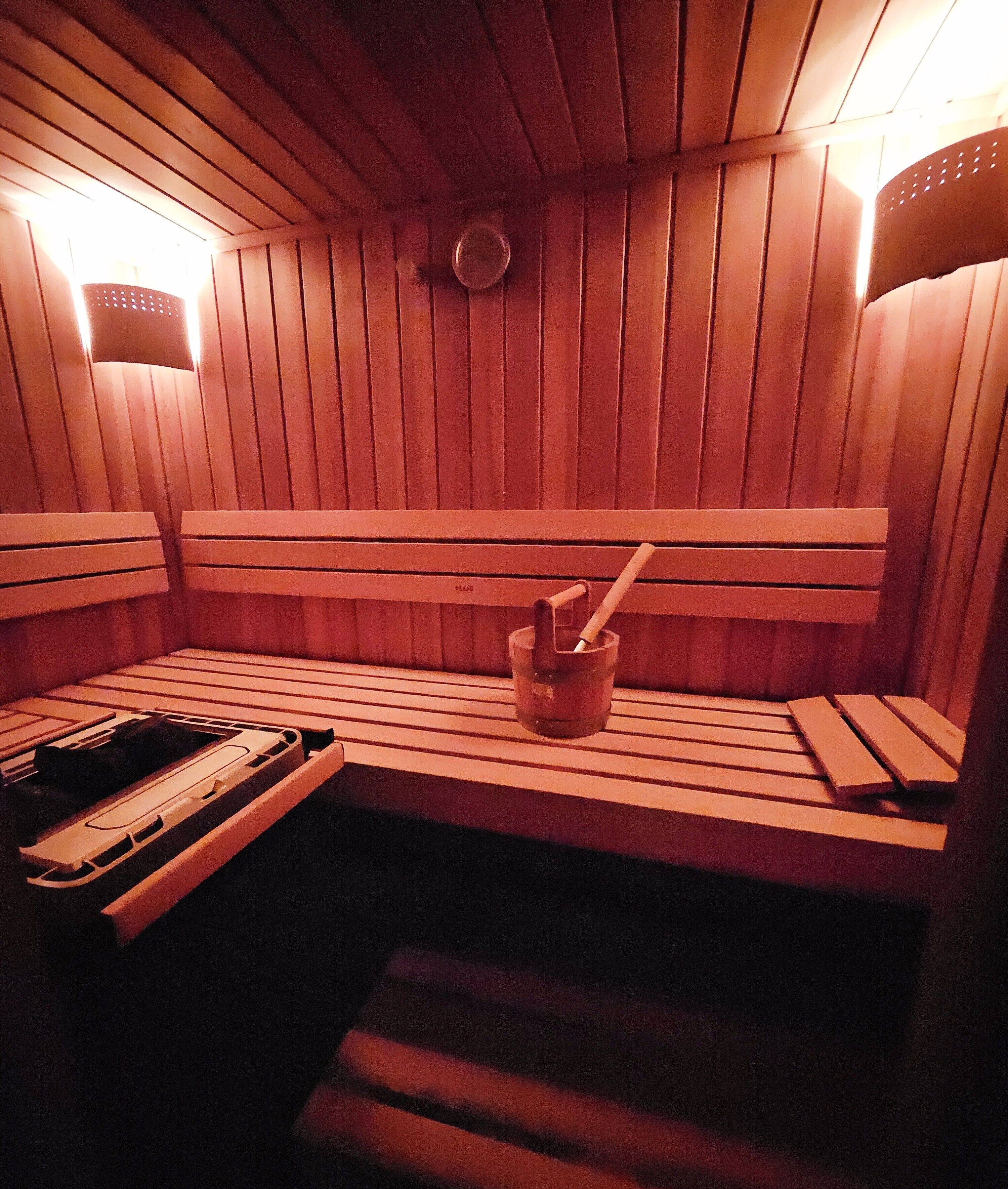 A sauna with wooden benches and a bench with a towel and a cup.