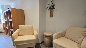 A modern living room with a sofa, a chair, a small round table, and an air conditioning unit mounted on the wall. - L'ECRIN VERT  (Kaysersberg-Vignoble)