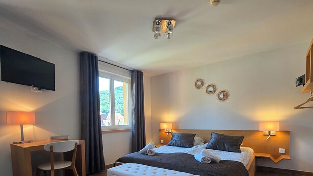 A bedroom with a bed, bedside tables, a desk, a chair, a TV, and a window with curtains. - L'ECRIN VERT  (Kaysersberg-Vignoble)