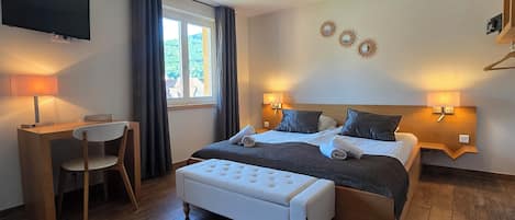 A bedroom with a bed, bedside tables, a desk, a chair, a TV, and a window with curtains.