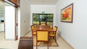 A conference room with a long table, chairs, a painting, and a window with a view of greenery. - Room-double Self-contained Room 6 (Johannesburg)