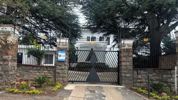 A gated entrance with a stone wall, a metal gate, and a sign indicating armed response and 24/7 CCTV. - Room-double Self-contained Room 6 (Johannesburg)