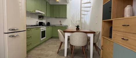 A compact kitchen with a refrigerator, stove, and dining area with chairs and a table.