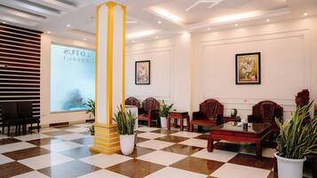 A lobby with a checkered floor, a large pillar, and traditional wooden furniture.
