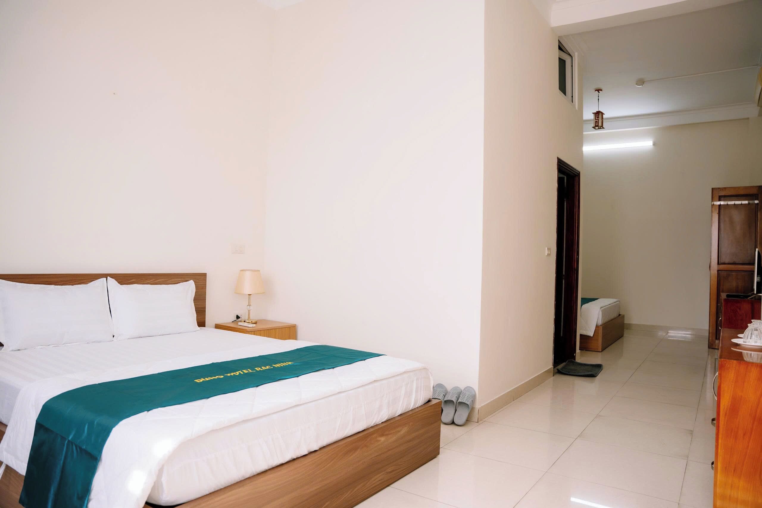 Una habitación de hotel con cama, mesita de noche, lámpara y armario de madera.
