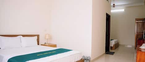 Una habitación de hotel con cama, mesita de noche, lámpara y armario de madera.