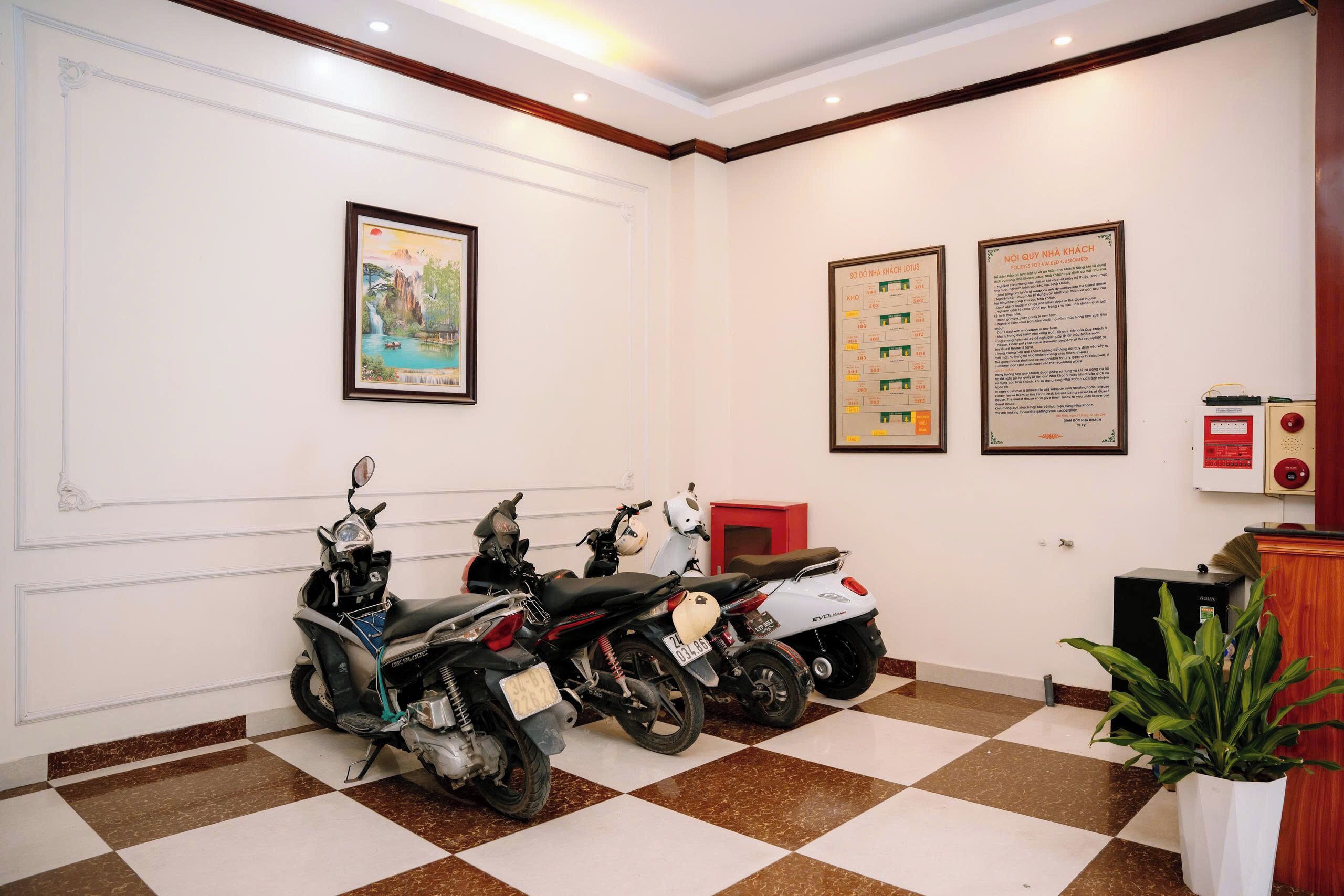 A clean, well-lit room with a checkered floor, two framed artworks, and three scooters parked against the wall.