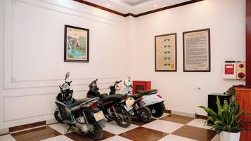 A clean, well-lit room with a checkered floor, two framed artworks, and three scooters parked against the wall.
