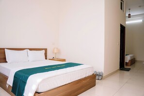 A hotel room with a wooden bed, white bedding, a teal bedspread, a bedside lamp, and a small wooden nightstand. - Lotus Hotel 1 (Hap Linh)