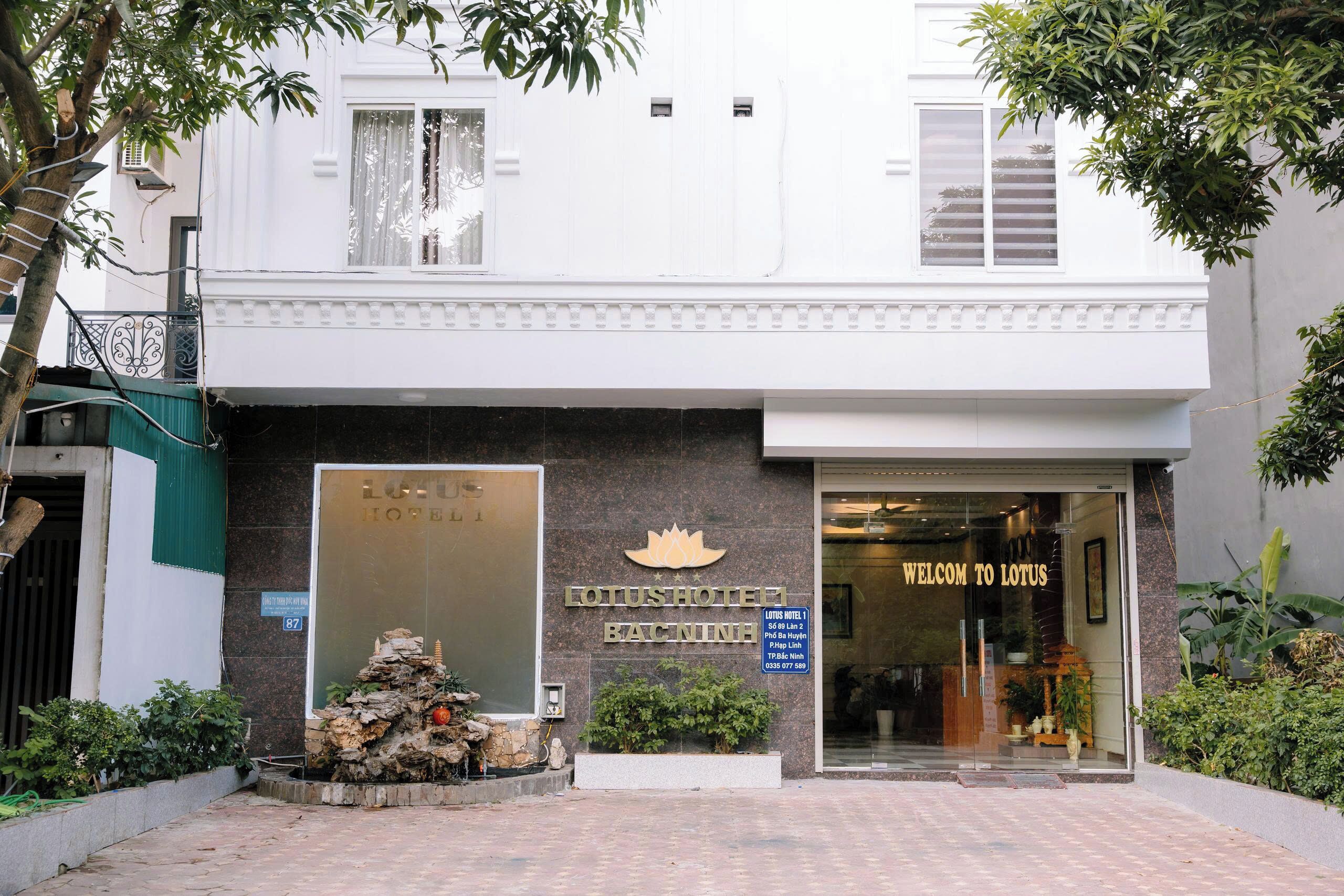 A hotel entrance with a sign reading 'LOTUS HOTEL BANCINH' and a welcome sign.