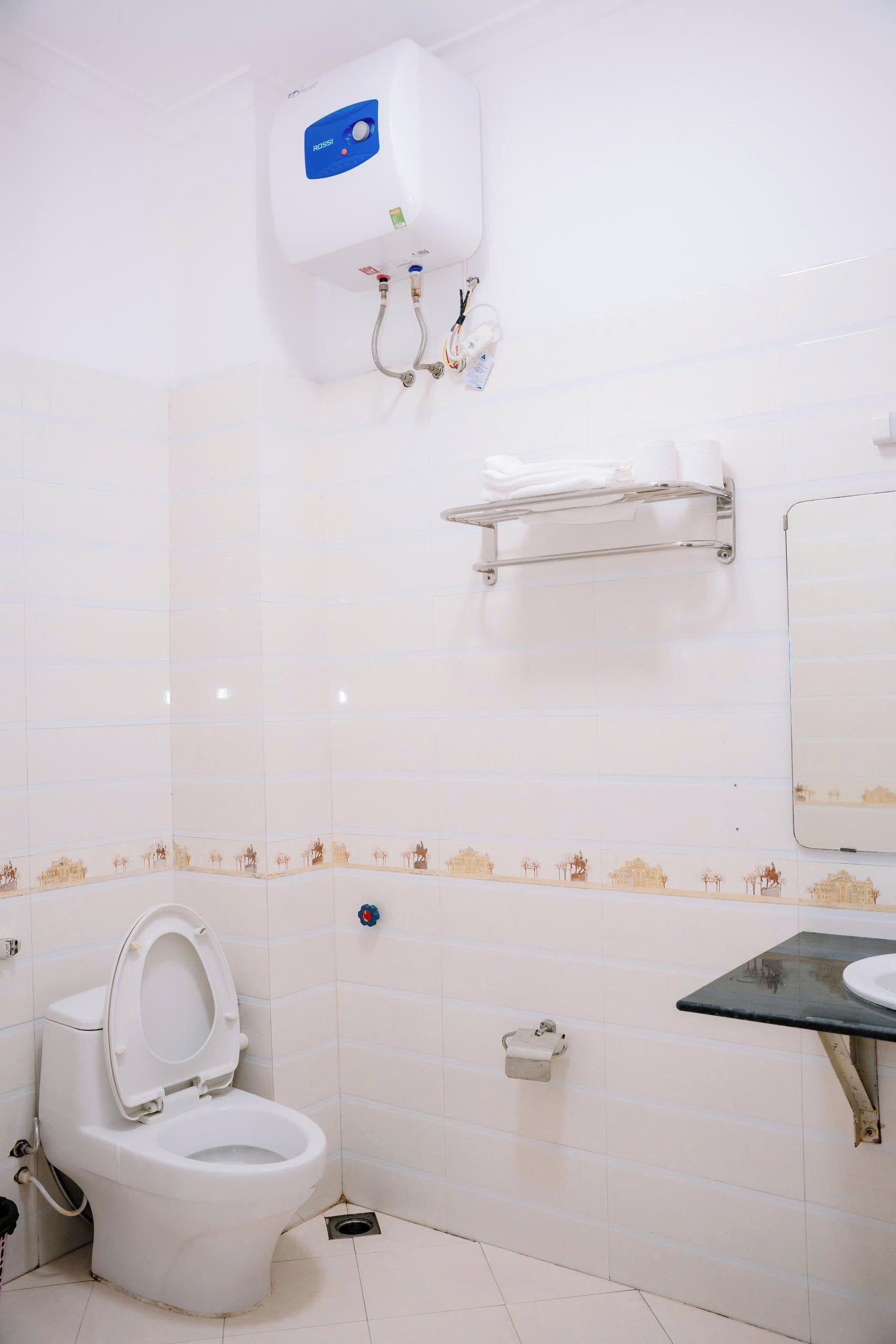 Un baño con inodoro, lavamanos, toallero y aire acondicionado de pared.
