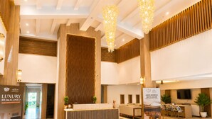 A spacious lobby with a reception desk, seating area, and a large chandelier.