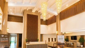 A modern hotel lobby with a reception desk, seating area, and a large chandelier. - Presidency Club Resort & Spa  (Vadodara)