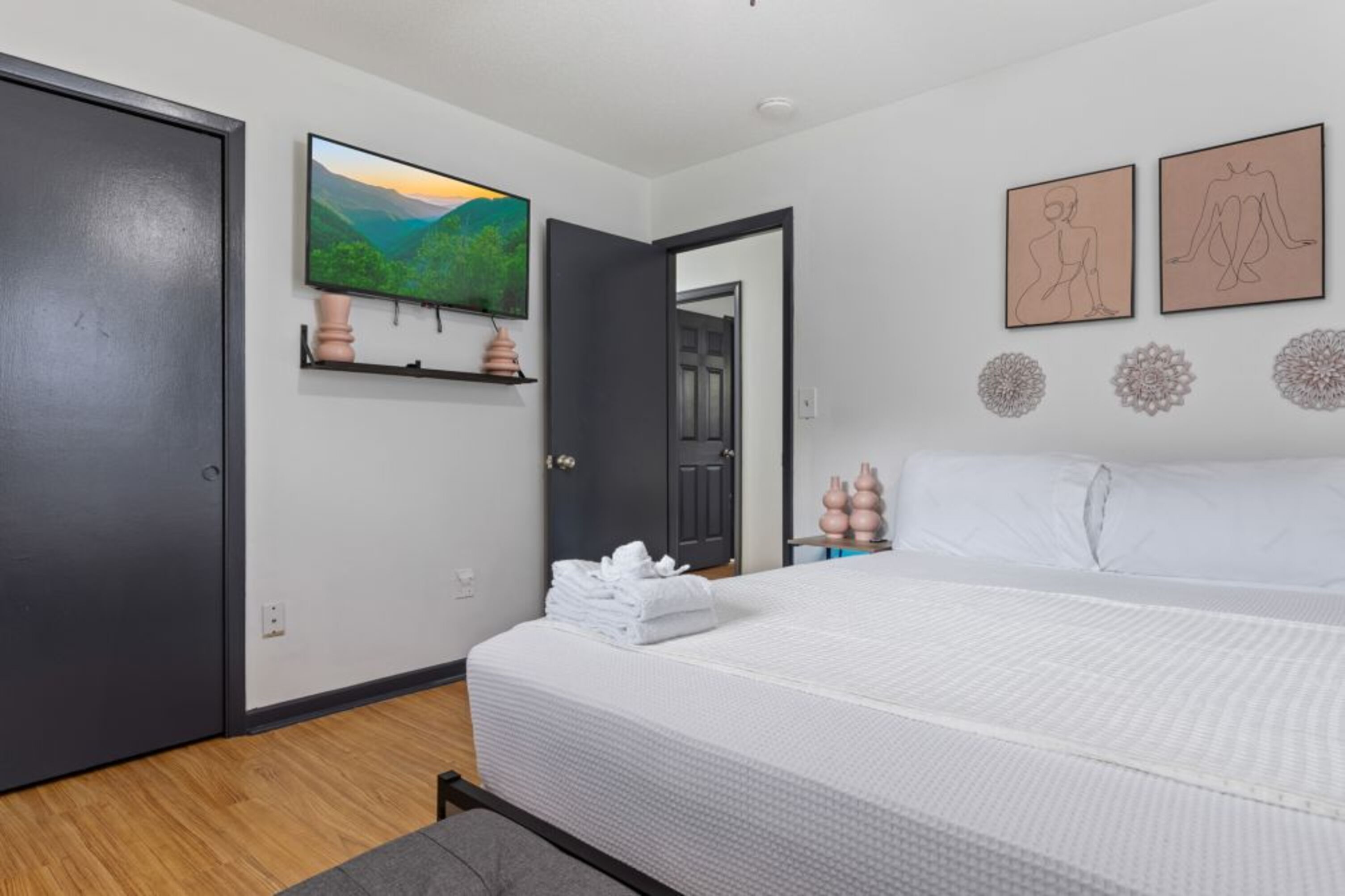 A modern bedroom with a bed, a TV, and artwork on the walls.