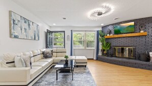 A modern living room with a sectional sofa, a coffee table, a fireplace, and a large painting on the wall. - Noir Manor (Sevierville)