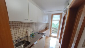 Eine Küche mit weißen Schränken, einer gefliesten Spritzschutzwand und einer Holz Arbeitsplatte.
