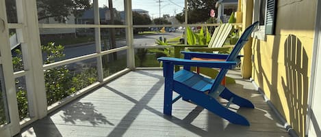 Une terrasse en bois avec une chaise bleue et un paillasson.