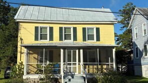 A two-story yellow house with green shutters, a covered porch, and a visible number '503' on the front.