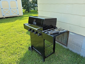 A charcoal grill with a control panel and multiple cooking tools.