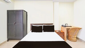 Ein Schlafzimmer mit einem Bett, einem Kleiderschrank, einem Schreibtisch mit Stuhl und einem kleinen Tisch mit Wasserkocher.
