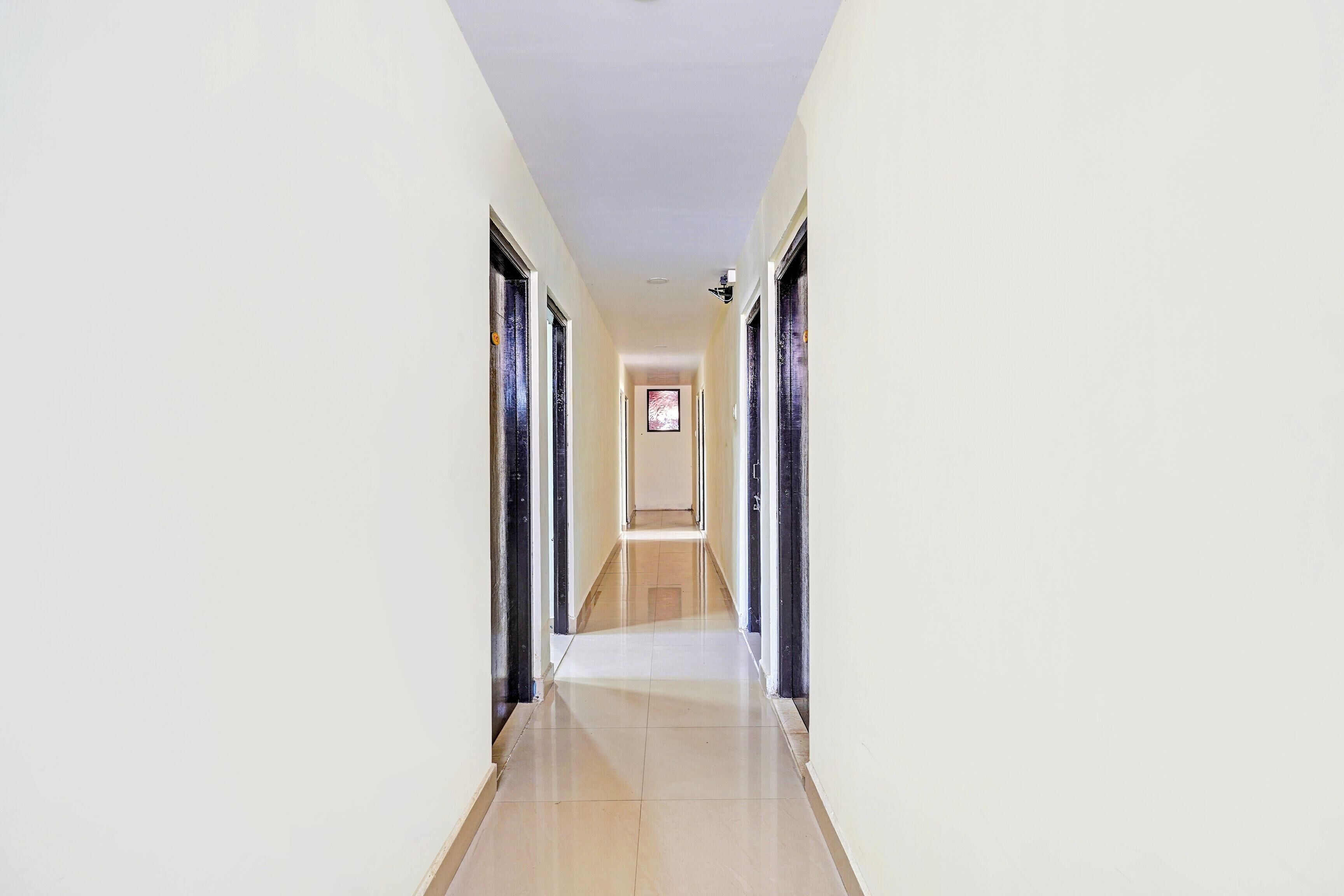 A long, narrow hallway with a tiled floor leading to a door at the end.