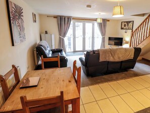 Ein Wohnzimmer mit einem Holzespeisetisch, zwei Sofas, einem Fernseher und einer Treppe.