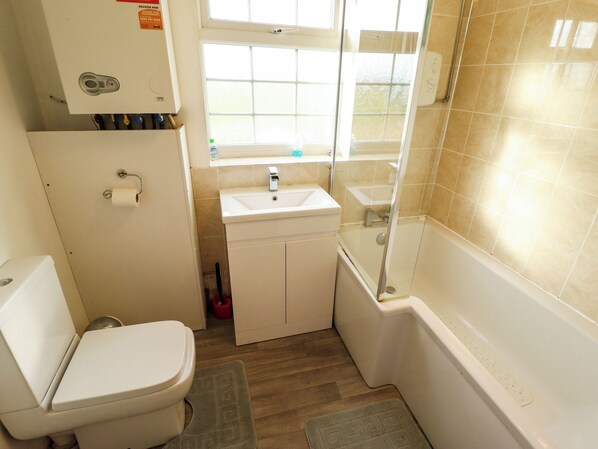 A compact bathroom with a toilet, sink, and shower. - Holiday Cottage 1 (Skegness)